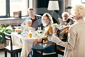 senior woman carrying thanksgiving turkey for holiday dinner