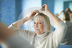 Senior woman checking hairline for hair loss