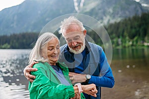 Senior woman checking her vital functions, heart rate, on smartwatch after hike.