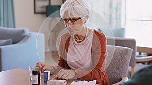 Senior woman checking medicine leaflet and taking a pill
