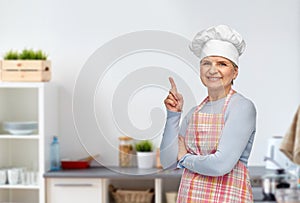 senior woman or chef pointing finger up at kitchen