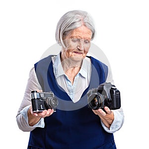 Senior woman choosing between old analogue camera and modern digital one