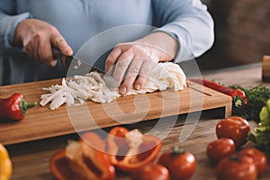 Senior woman chopping onion for salad