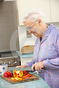 Senior woman chopping vegetables in kitchen