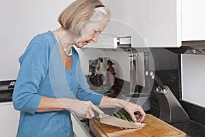 Senior woman chopping vegetables at kitchen counter