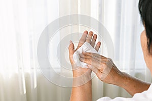 Senior woman cleaning her hands with white soft tissue paper.  on a white backgrounds