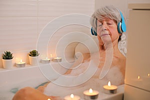 Senior woman closing her eyes in the bathtub while listening to music