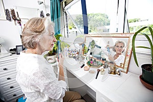 Senior woman combing her hair at dresser in house