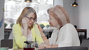 Senior woman comforting her upset daughter at the cafe