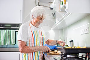Senior woman cooking in the kitchen - eating and cooking healthy