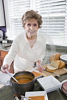 Senior woman cooking soup in kitchen
