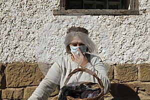 A senior woman, correctly adjusts her protective face mask, Spain