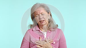 Senior woman coughing and clutching chest, expression of discomfort