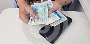 Senior woman counts israeli cash money