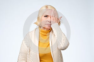 Senior woman covering one eye with her hand