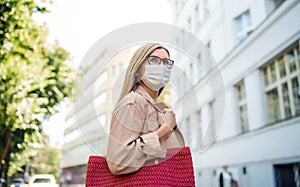 Senior woman crossing street outdoors in city or town, coronavirus concept.