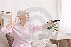 Senior woman cupping her hand behind ear to hear better