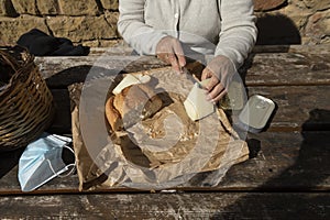 A senior woman, cuts slices of goat cheese, Spain