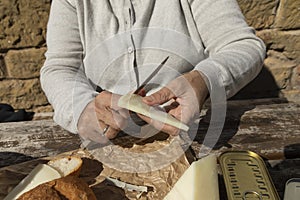 A senior woman, cuts slices of goat cheese, Spain