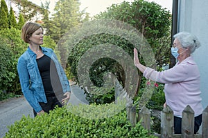 Senior Woman Demonstrating A Safe Distance With Her Neighbour 