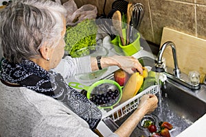 Senior woman disinfecting fruits and vegetables purchased during the COVID-19 pandemic