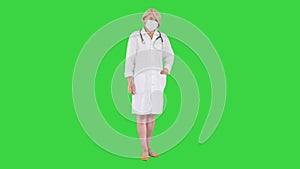 Senior woman doctor putting on medical mask looking at the camera on a Green Screen, Chroma Key.