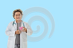 senior woman doctor with stethoscope smile holding heart on blue background.healthcare and medical concept