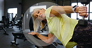 Senior woman doing dumbbell row exercise in fitness studio 4k