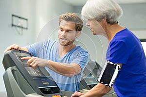 Senior woman doing exercise on bike with young coach