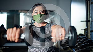 Senior woman doing exercise with dumbbells in gym, coronavirus concept.