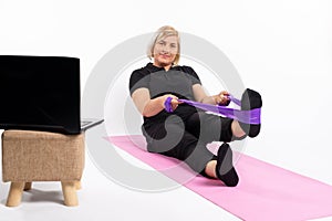 Senior woman doing exercise with an elastic band. Online training in quarantine