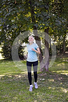 Senior woman doing exercise in green park at summer day