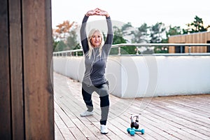 A senior woman doing exercise outdoors, stretching.