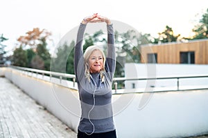 A senior woman doing exercise outdoors, stretching.