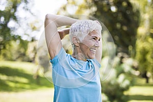 Senior woman doing exercise for stretching hand in the park