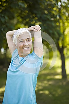 Senior woman doing exercise for stretching hand in the park