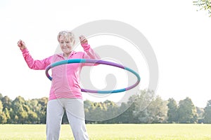 Senior woman doing gymnastic with hula hoop in park