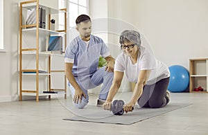 Senior woman doing physical exercise with abdominal roller at physiotherapy room