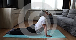 Senior woman doing pilates exercises with stretching on her yoga mat