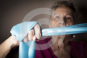 Senior woman doing rehabilitation exercises with elastic band