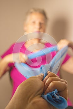 Senior woman doing rehabilitation exercises with elastic band