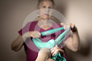 Senior woman doing rehabilitation exercises with elastic band
