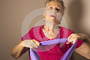 Senior woman doing rehabilitation exercises with elastic band