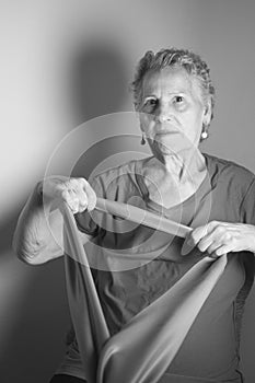 Senior woman doing rehabilitation exercises with elastic band