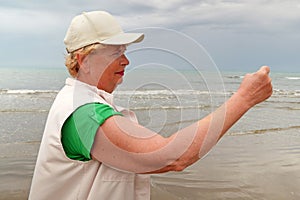 Senior woman doing sport to keep fit. Mature woman running along the shore of the beach. Concept of healthy life in the elderly.