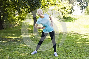 Senior woman doing streching exercise in the park