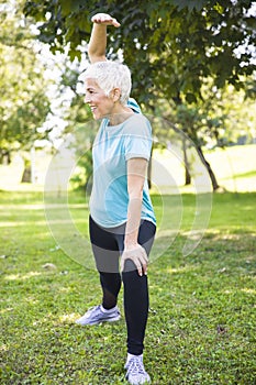 Senior woman doing streching exercise in the park