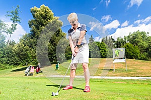 Senior woman doing tee stroke on golf course