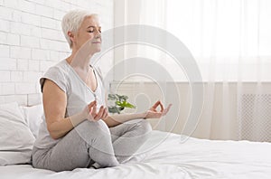 Senior woman doing yoga on bed at home