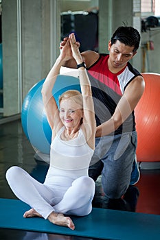 Senior woman Doing yoga in fitness gym. aged lady exercising Personal trainer man . Old female workout .Mature sport training.